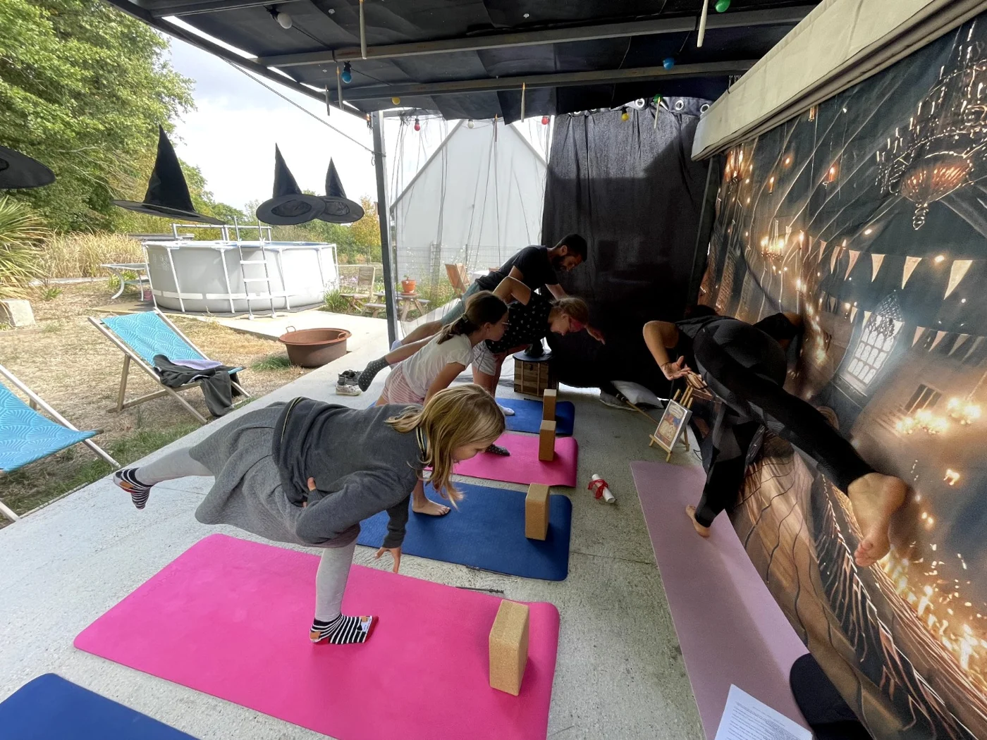 Enfants et adultes explorent ensemble une posture d’équilibre pendant le yoga magique